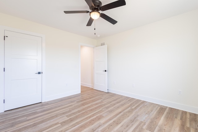 empty room featuring ceiling fan, light wood-style floors, visible vents, and baseboards