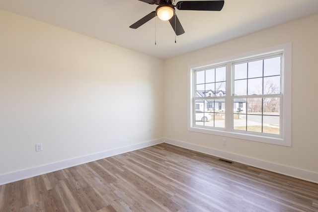 spare room featuring wood finished floors, visible vents, and baseboards