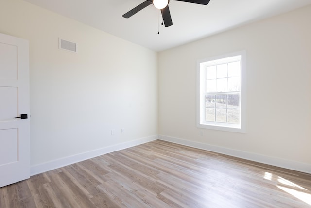 unfurnished room featuring a ceiling fan, visible vents, baseboards, and wood finished floors