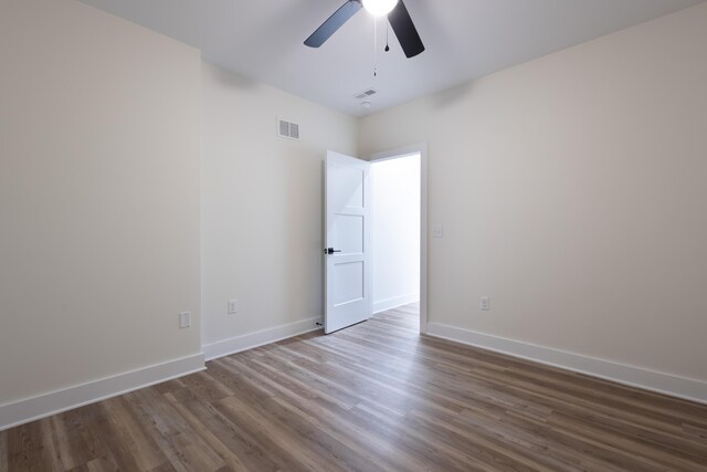 empty room featuring visible vents, ceiling fan, baseboards, and wood finished floors