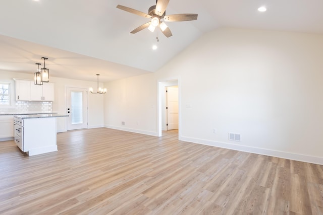 unfurnished living room with lofted ceiling, ceiling fan with notable chandelier, visible vents, baseboards, and light wood finished floors