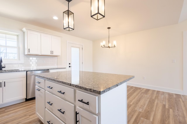 kitchen featuring decorative backsplash, light wood-style flooring, a kitchen island, stainless steel dishwasher, and a sink