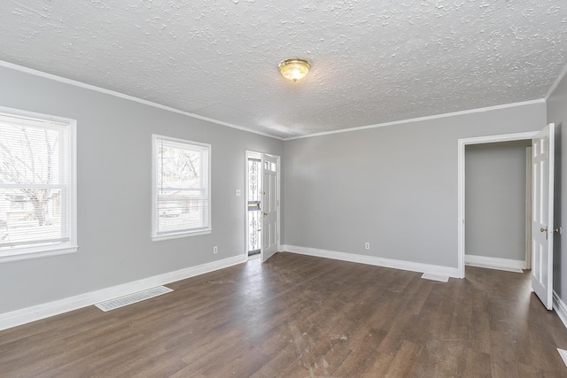 empty room with visible vents, dark wood-type flooring, baseboards, and ornamental molding