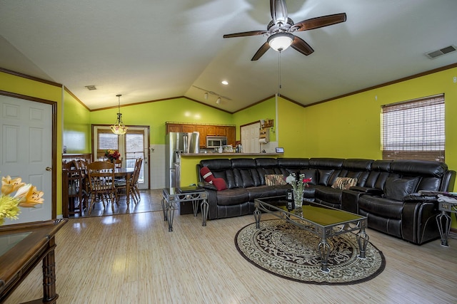 living area with a wealth of natural light, visible vents, ornamental molding, light wood finished floors, and lofted ceiling