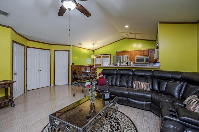 living area featuring visible vents, crown molding, light wood-type flooring, and vaulted ceiling