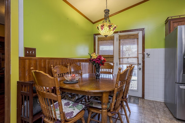 dining area with light tile patterned flooring, wainscoting, ornamental molding, and vaulted ceiling