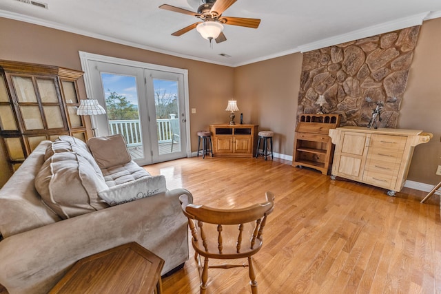 living area with light wood finished floors, visible vents, baseboards, a ceiling fan, and crown molding