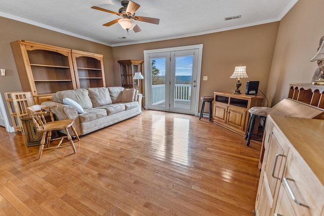 living room featuring a ceiling fan, visible vents, light wood-style floors, and crown molding