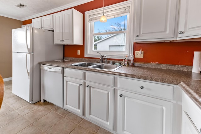 kitchen featuring white cabinets, dark countertops, a sink, white dishwasher, and crown molding