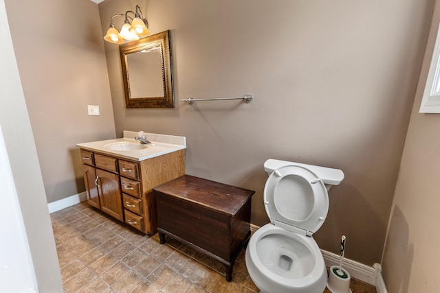 bathroom featuring toilet, baseboards, and vanity