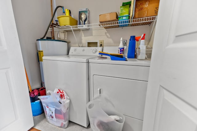 laundry area with water heater, washing machine and clothes dryer, and laundry area