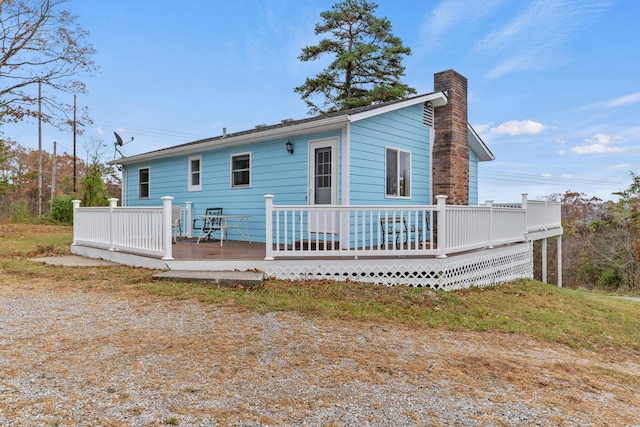 back of house featuring a chimney and a wooden deck