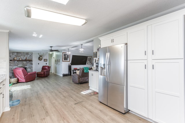 kitchen featuring a textured ceiling, light wood-style flooring, vaulted ceiling, open floor plan, and stainless steel fridge