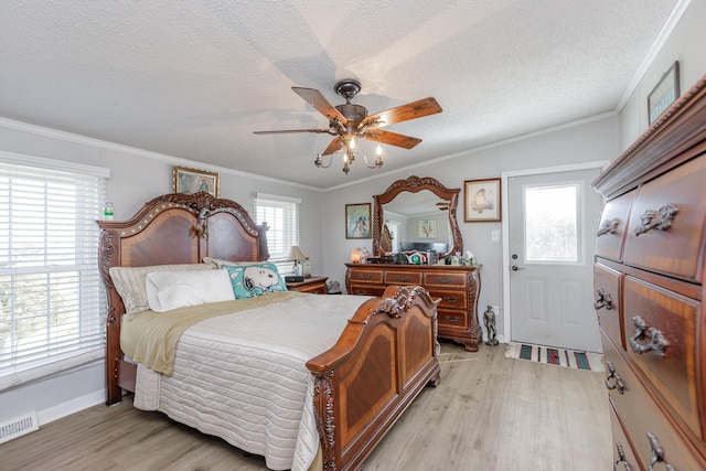 bedroom with a textured ceiling, ceiling fan, visible vents, light wood-style floors, and ornamental molding