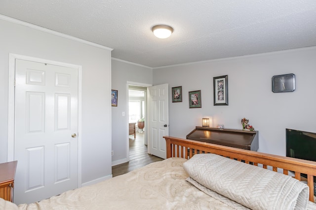 bedroom with crown molding, a textured ceiling, baseboards, and wood finished floors