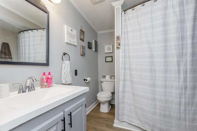 full bathroom featuring toilet, ornamental molding, wood finished floors, a textured ceiling, and vanity