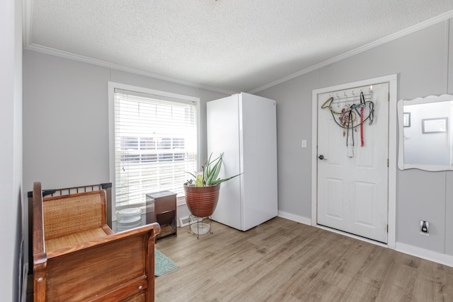 living area with a textured ceiling, light wood-style floors, baseboards, and crown molding