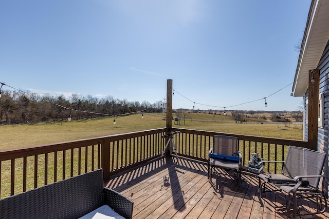 wooden terrace with a rural view and a lawn