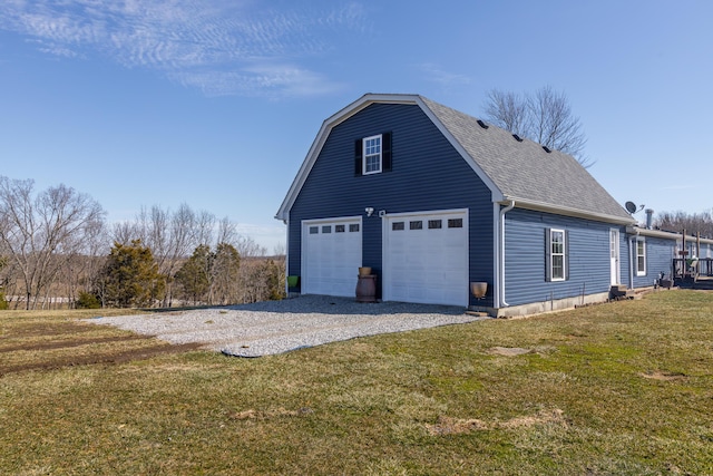 view of side of home featuring a garage, a yard, roof with shingles, and a gambrel roof