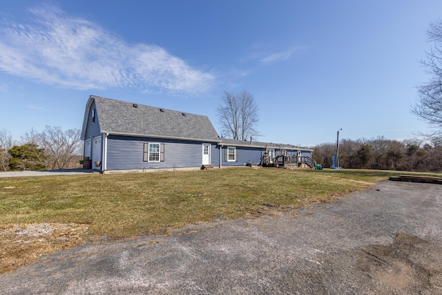 exterior space with a garage, roof with shingles, and a front lawn