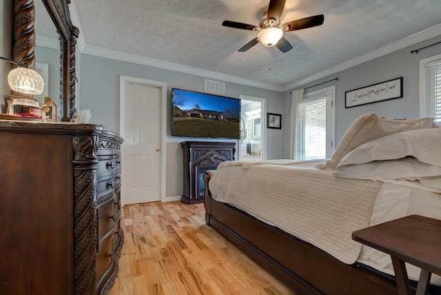 bedroom featuring ornamental molding, ceiling fan, a textured ceiling, and light wood finished floors