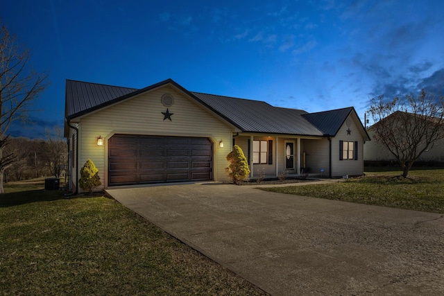 ranch-style home with a garage, metal roof, a front lawn, and concrete driveway