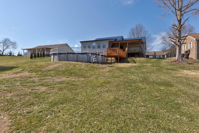 rear view of house featuring a yard, a wooden deck, and a covered pool