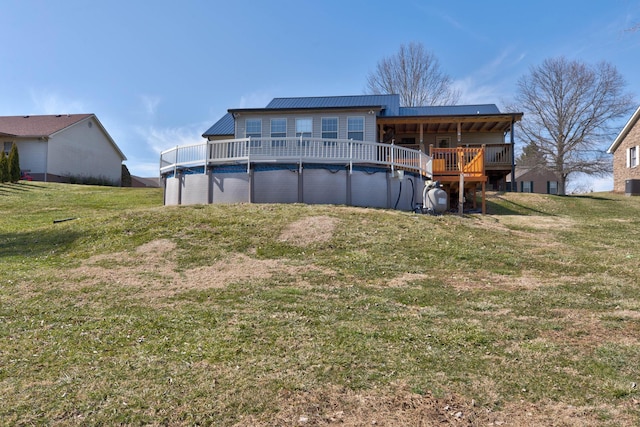 rear view of property featuring a covered pool, metal roof, a lawn, and a wooden deck