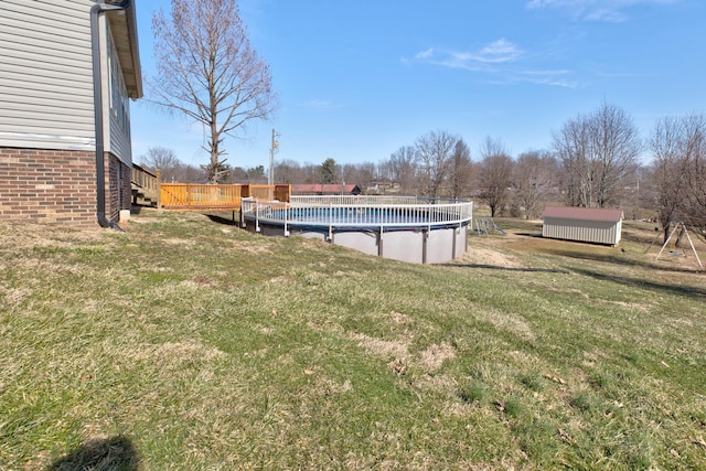 view of yard featuring a covered pool, a shed, a deck, and an outbuilding