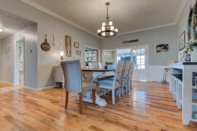 dining space featuring light wood-style floors, crown molding, a chandelier, and a textured ceiling