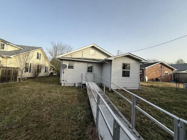 rear view of property featuring fence and a lawn