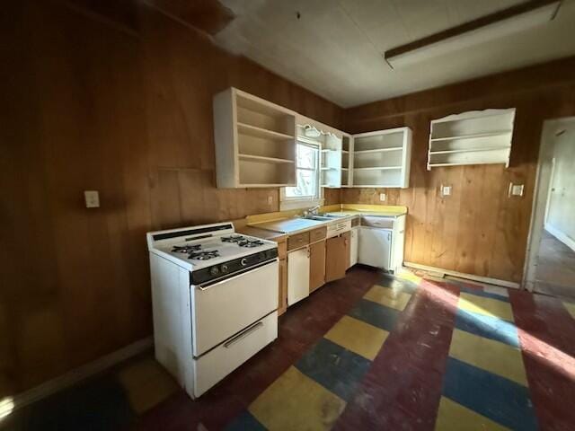 kitchen featuring wood walls, a sink, light countertops, white gas range oven, and open shelves