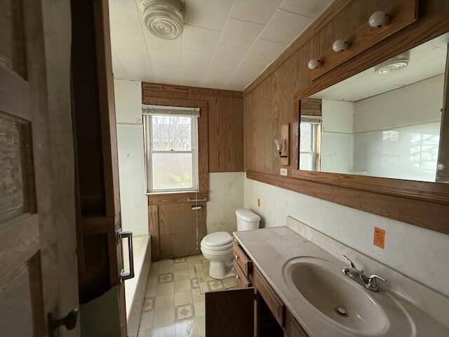 bathroom with toilet, a tub, and vanity