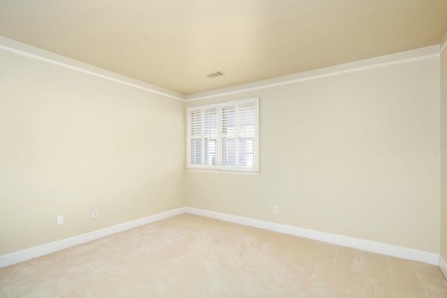 spare room featuring light colored carpet, visible vents, and baseboards