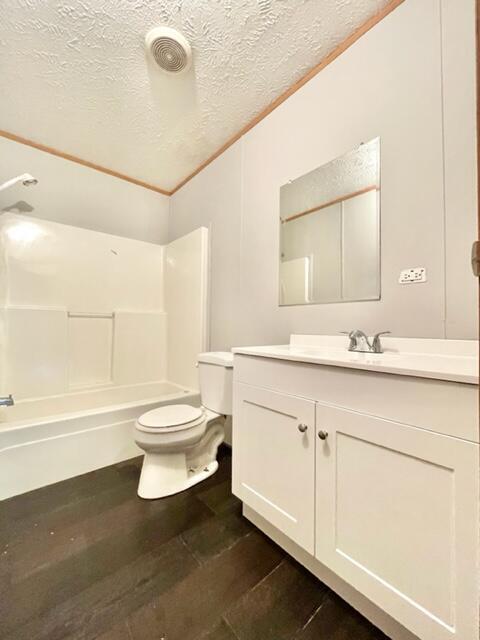 bathroom with a textured ceiling, toilet, wood finished floors, vanity, and washtub / shower combination