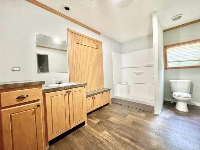 full bath with toilet, wood finished floors, vanity, a shower, and crown molding