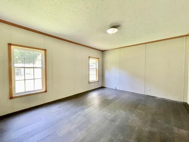 empty room with a textured ceiling, ornamental molding, and dark wood finished floors