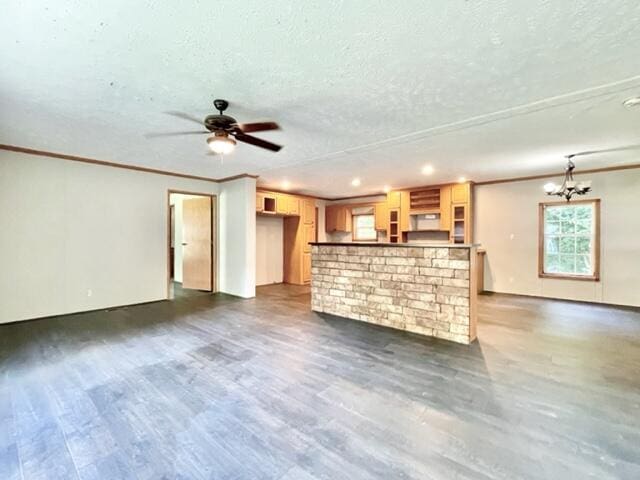 unfurnished living room with a textured ceiling, ornamental molding, dark wood-style flooring, and ceiling fan with notable chandelier