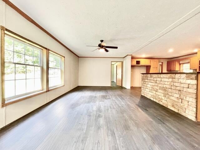 unfurnished living room with a textured ceiling, ceiling fan, dark wood finished floors, and crown molding