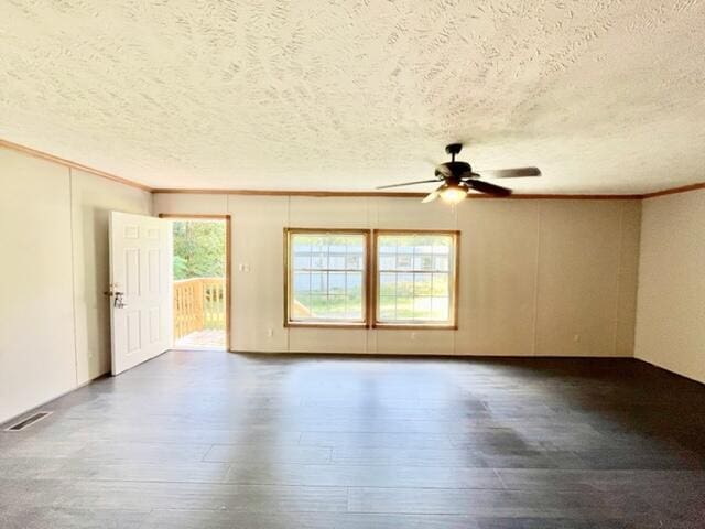 empty room featuring visible vents, wood finished floors, and ornamental molding