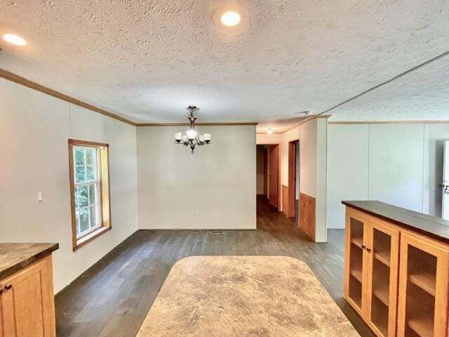 unfurnished room featuring dark wood-style floors, a notable chandelier, crown molding, and a textured ceiling