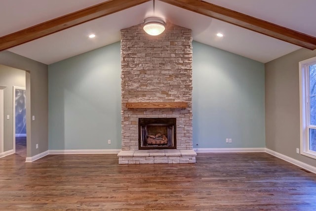 unfurnished living room with a stone fireplace, lofted ceiling with beams, wood finished floors, and baseboards