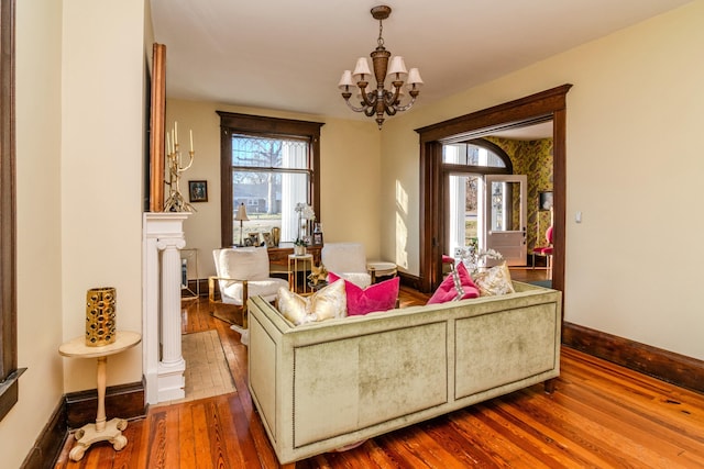 living room featuring an inviting chandelier, wood-type flooring, and baseboards