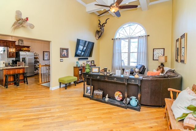 office featuring light wood finished floors, baseboards, ceiling fan, beamed ceiling, and a high ceiling