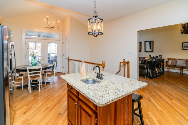 kitchen with light wood-type flooring, freestanding refrigerator, brown cabinets, and a sink