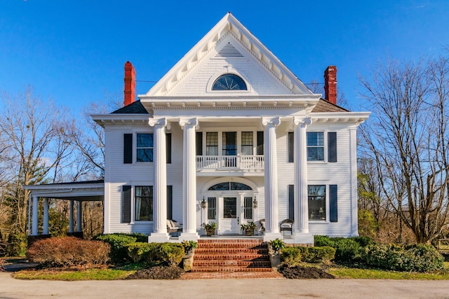 neoclassical home featuring covered porch, french doors, a chimney, and a balcony