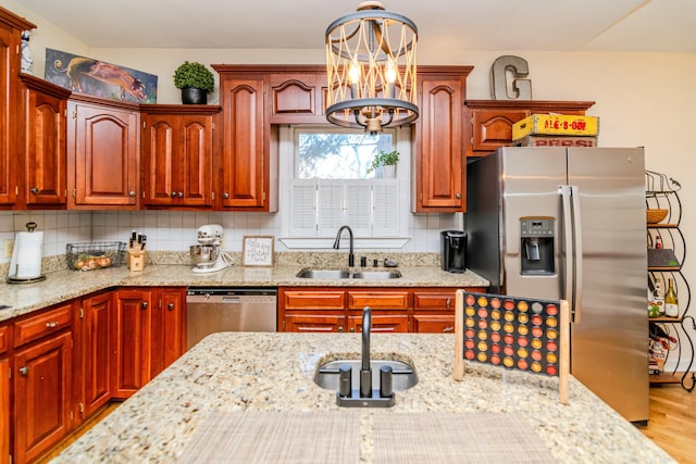 kitchen featuring decorative backsplash, light stone counters, wood finished floors, stainless steel appliances, and a sink