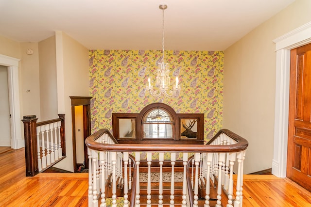 interior space featuring an inviting chandelier, wood finished floors, and an upstairs landing