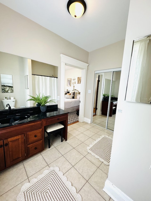 ensuite bathroom with connected bathroom, vanity, baseboards, and tile patterned floors