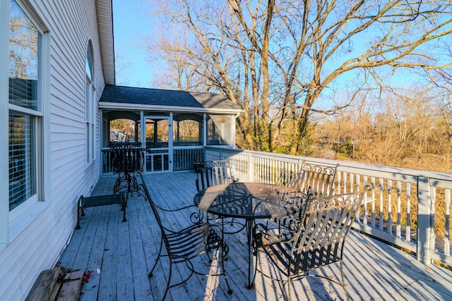 wooden terrace with a sunroom and outdoor dining area